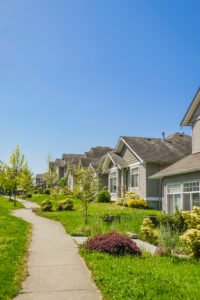 A perfect neighborhood. Concrete pathway along the row of residential houses on a sunny day with blue sky background